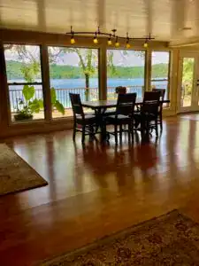 dining area taken from living room with bright blue lake outside the giant windows