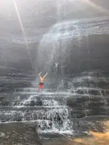 boy standing under a giant waterfall