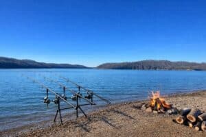 carp fishing poles lining the shoreline of dale hollow lake, with a bonfire burning closeby.