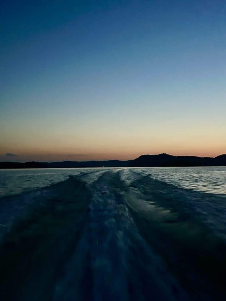 Boat wake on still water at sunset.