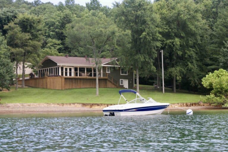 Ski Boat floating on white buoy in front of Lake House