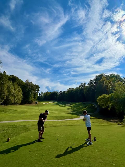 Two golfers driving from the tee looking down the fareway.